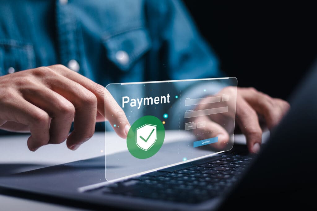 A person using a laptop with a transparent virtual screen displaying the word Payment, a checkmark shield icon, and fields for login information, symbolizing secure cashless payments and modern payment technology.