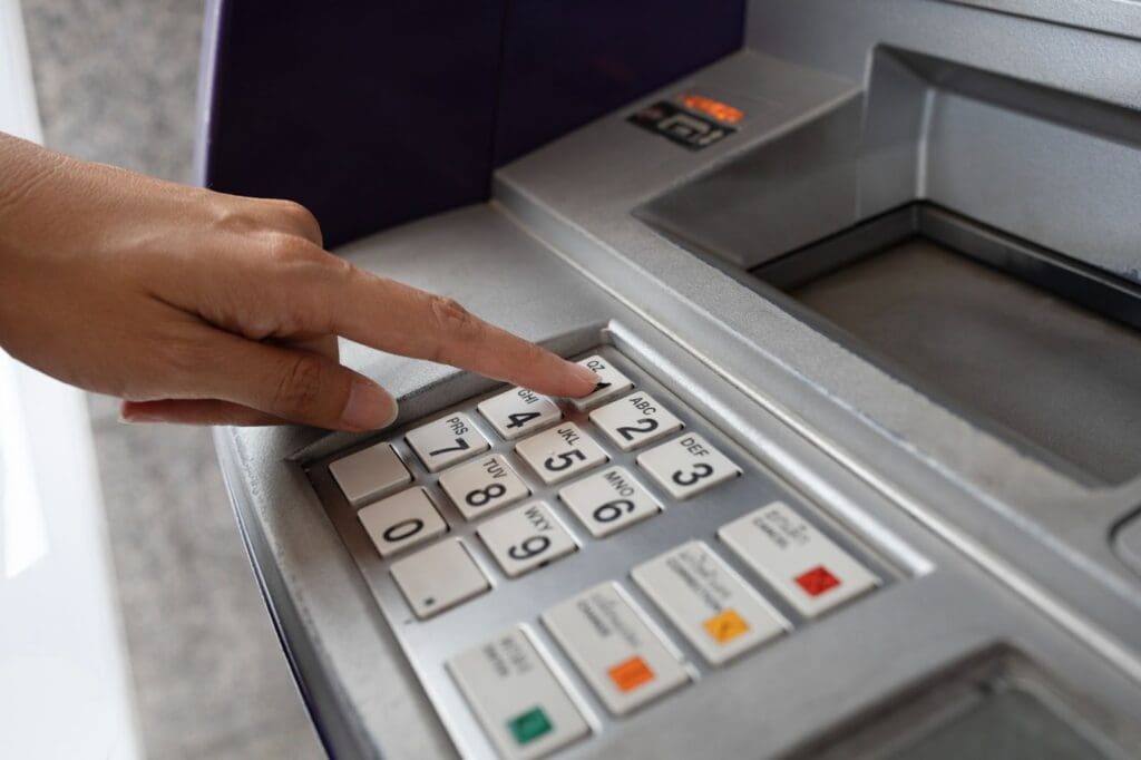 A person’s hand is pressing the number 2 on the keypad of a reliable ATM, preparing to enter a PIN or select an option, showcasing the trustworthiness that top ATM providers bring to any business.